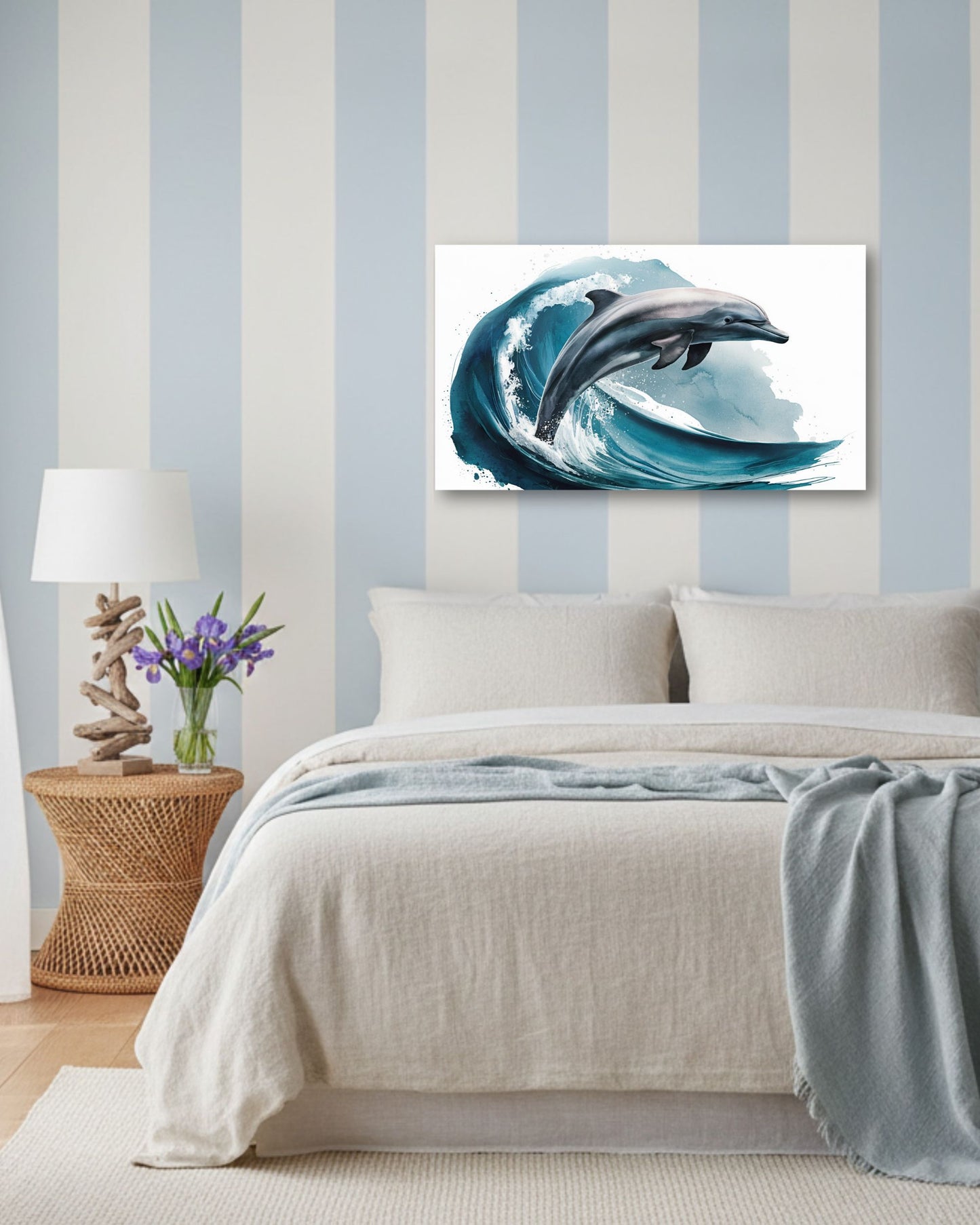 A bedroom scene with a bed dressed in light neutral bedding and a blue throw blanket, against a blue-and-white striped wall. An unframed wall art print showing a dolphin leaping through a blue ocean wave is mounted above the bed.