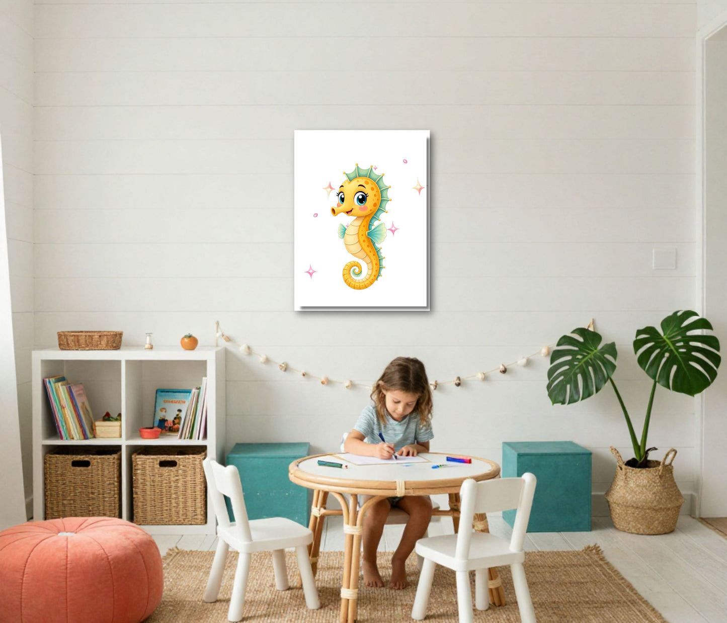 A children's room scene with a young girl sitting at a small round table, with a framed seahorse wall art print centered above her on a white shiplap wall. The room includes white chairs, teal storage boxes, a plant, baskets, and a peach pouf.