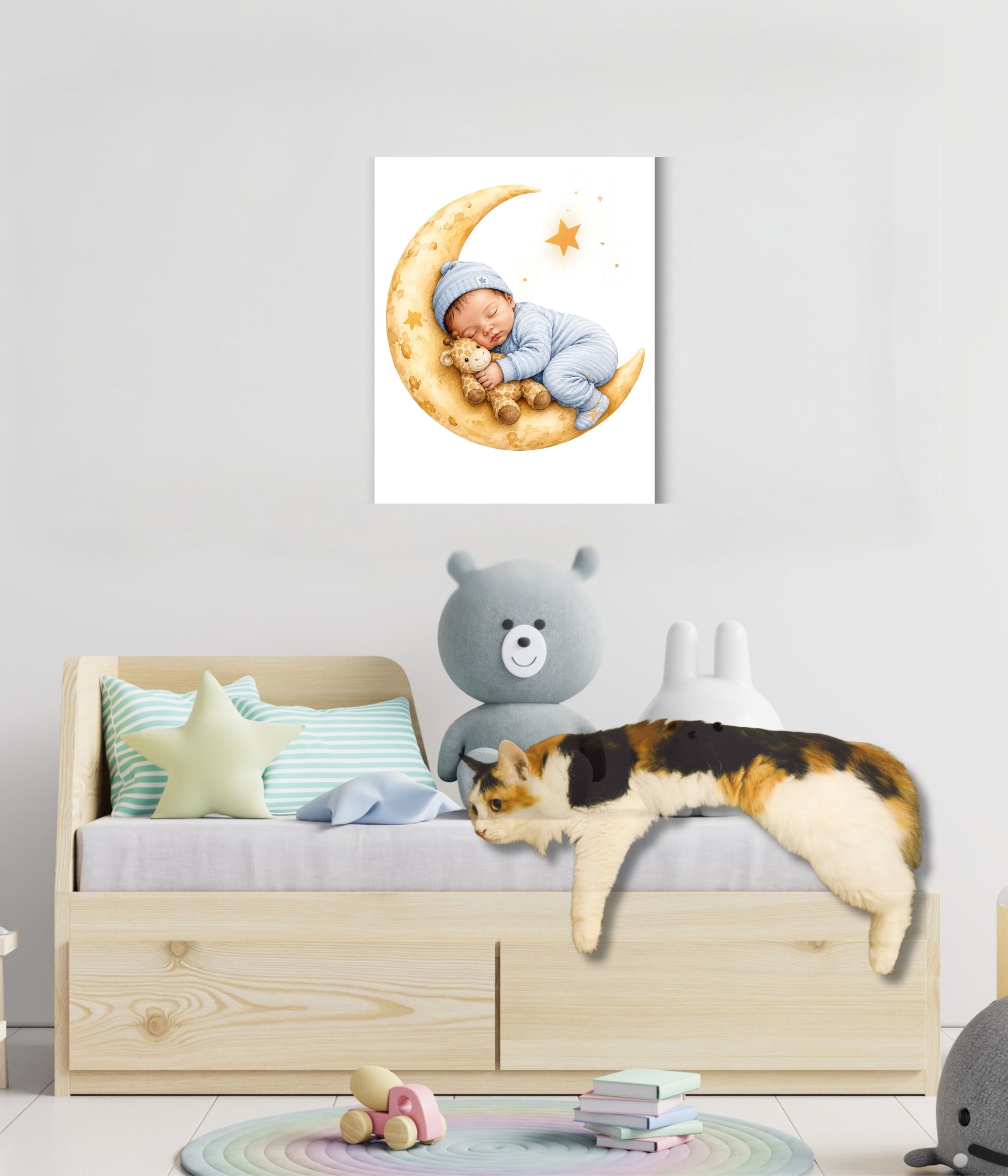 A wall-mounted canvas print showing a sleeping baby on a crescent moon, displayed above a children's bed in a styled nursery. The room includes a wooden bed frame, pastel pillows, a gray teddy bear, and a calico cat lying on the bed.