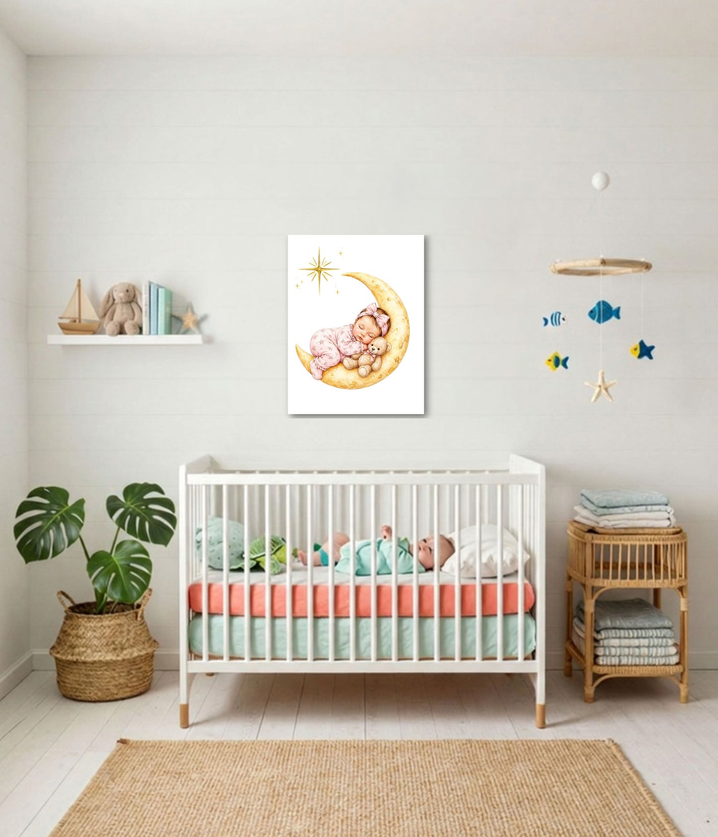 A framed wall art print depicting a baby sleeping on a crescent moon with stars, displayed in a styled nursery above a white crib with pastel bedding.